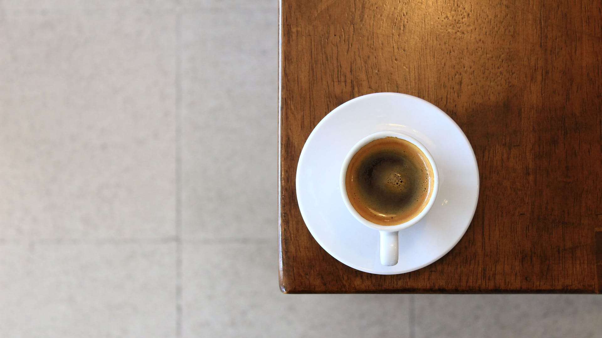 Overhead view of an espresso in a white cup on a wooden table